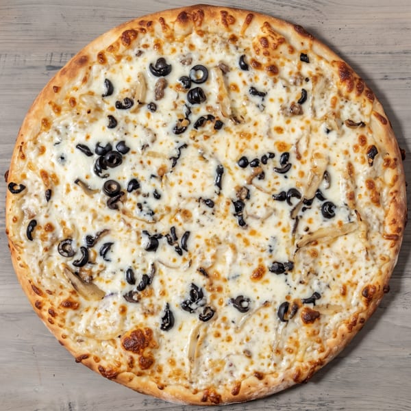 White sauce pizza with black olives and mushrooms on a wooden surface.